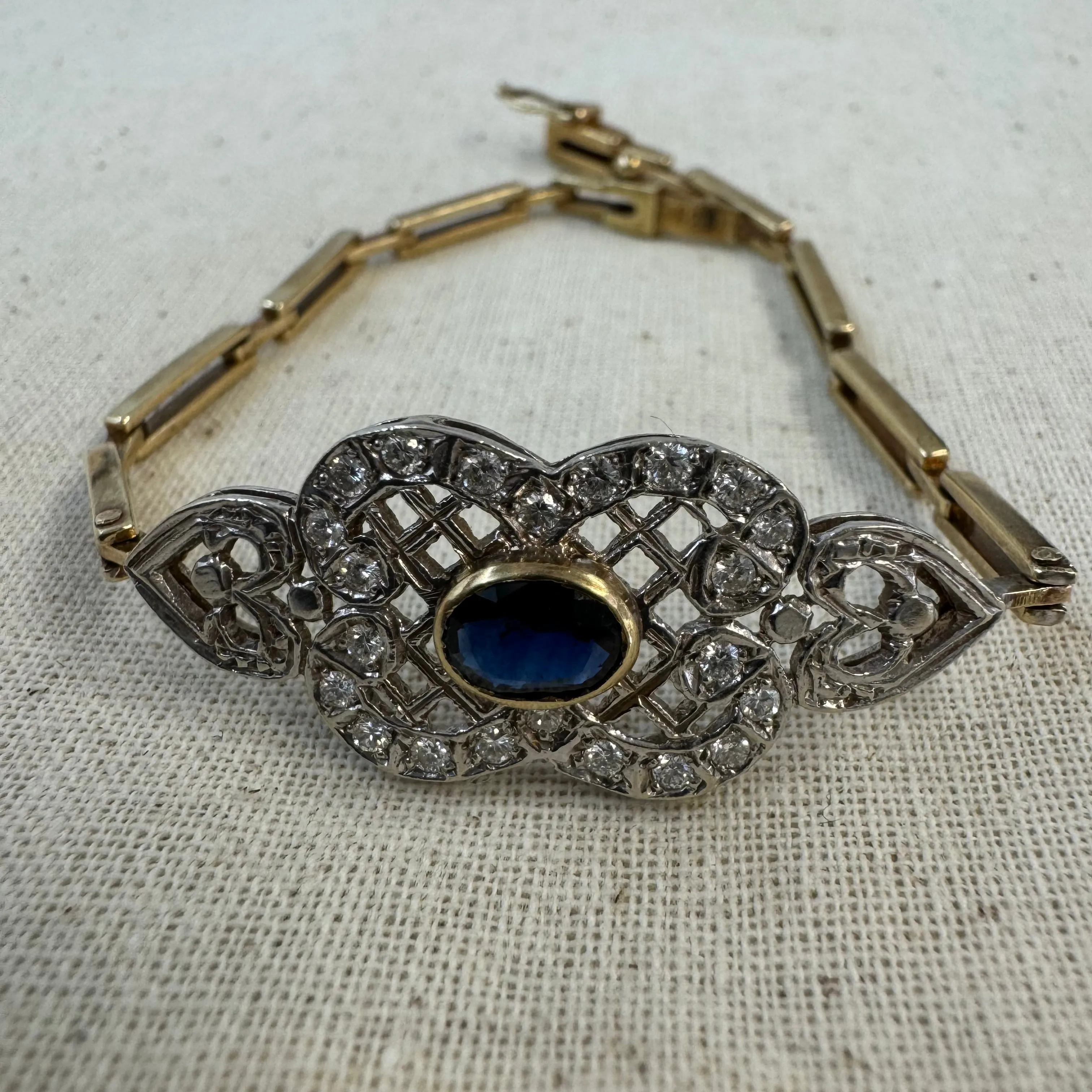 14K gold bracelet set with a central deep-blue Sapphire surrounded by sparkling Diamonds