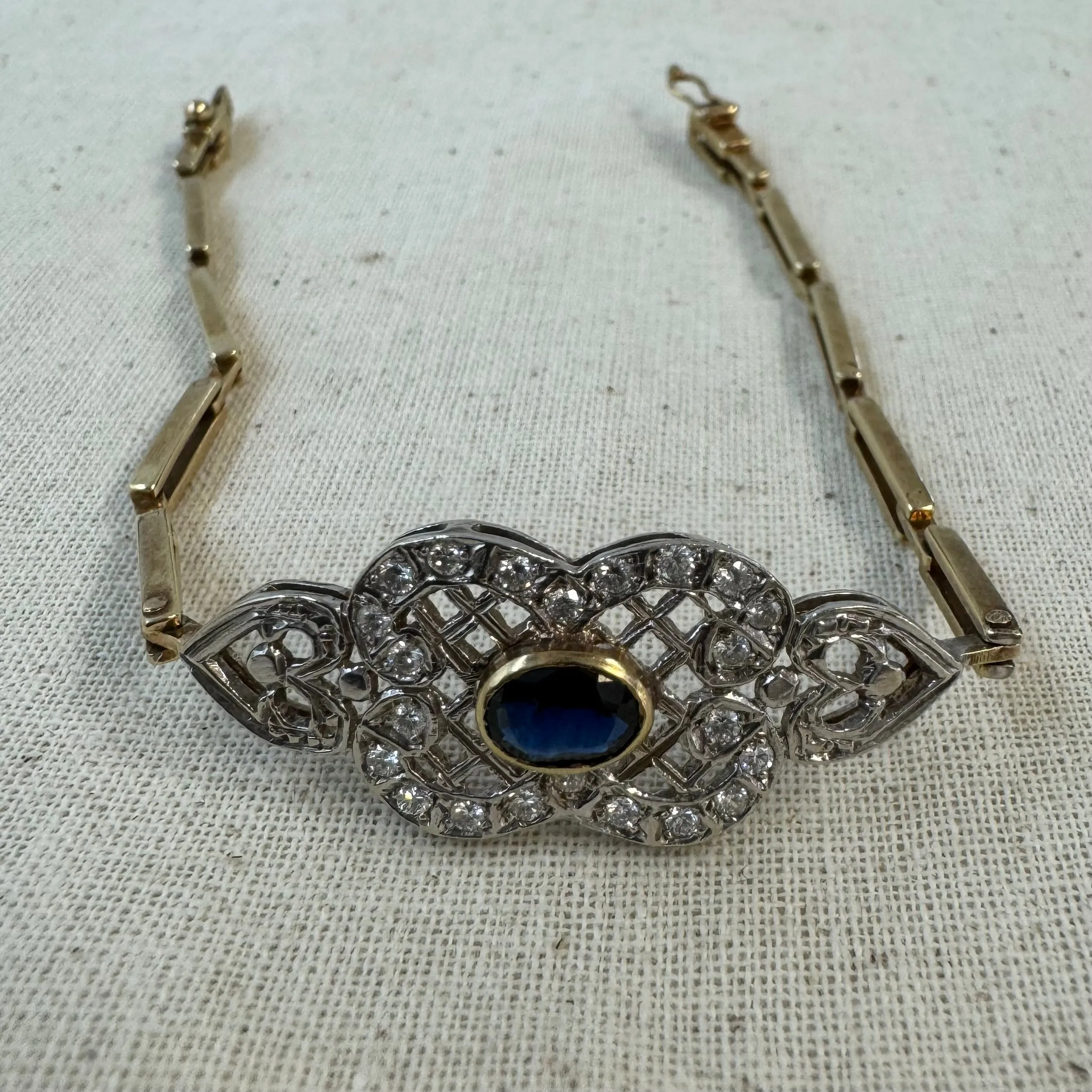 14K gold bracelet set with a central deep-blue Sapphire surrounded by sparkling Diamonds