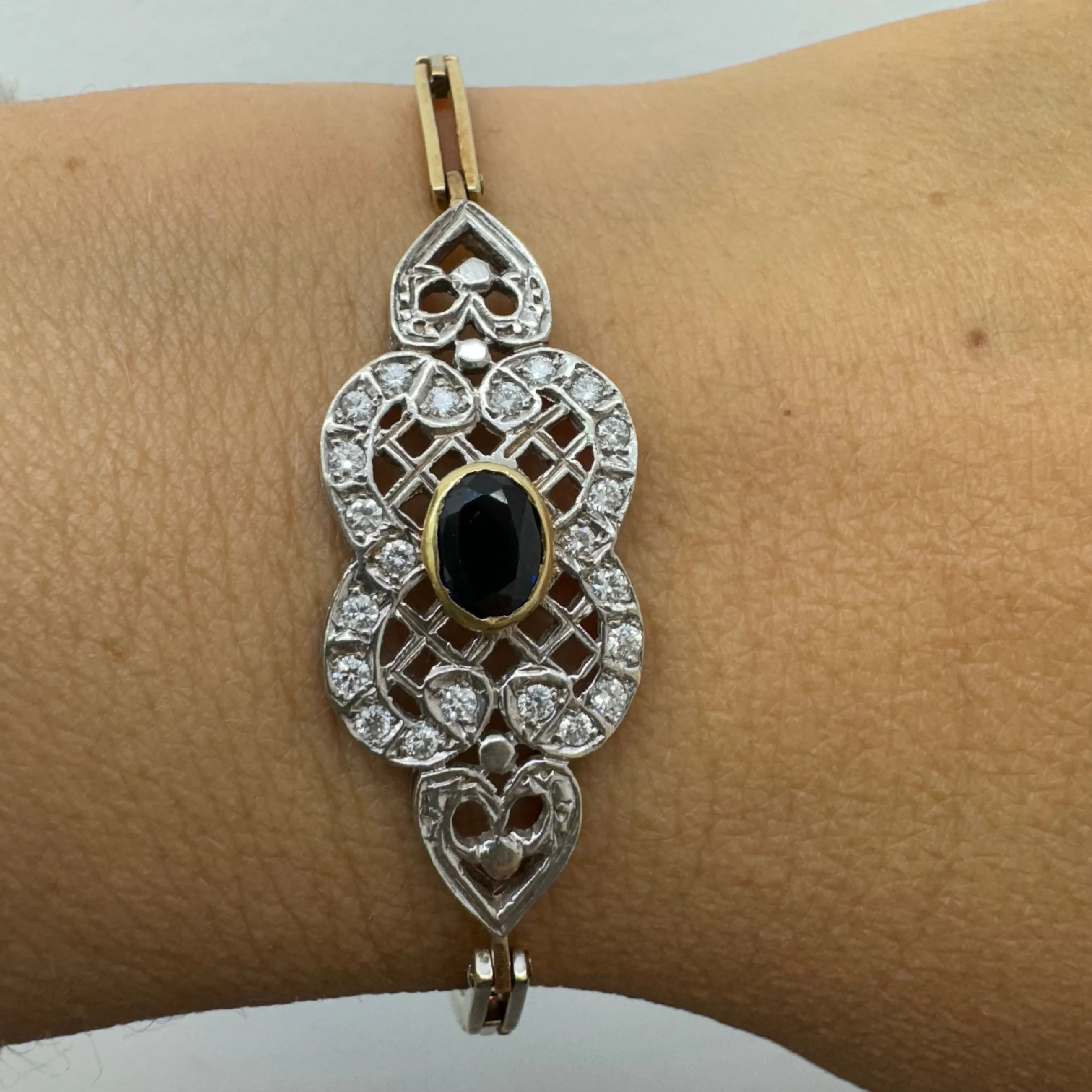 14K gold bracelet set with a central deep-blue Sapphire surrounded by sparkling Diamonds
