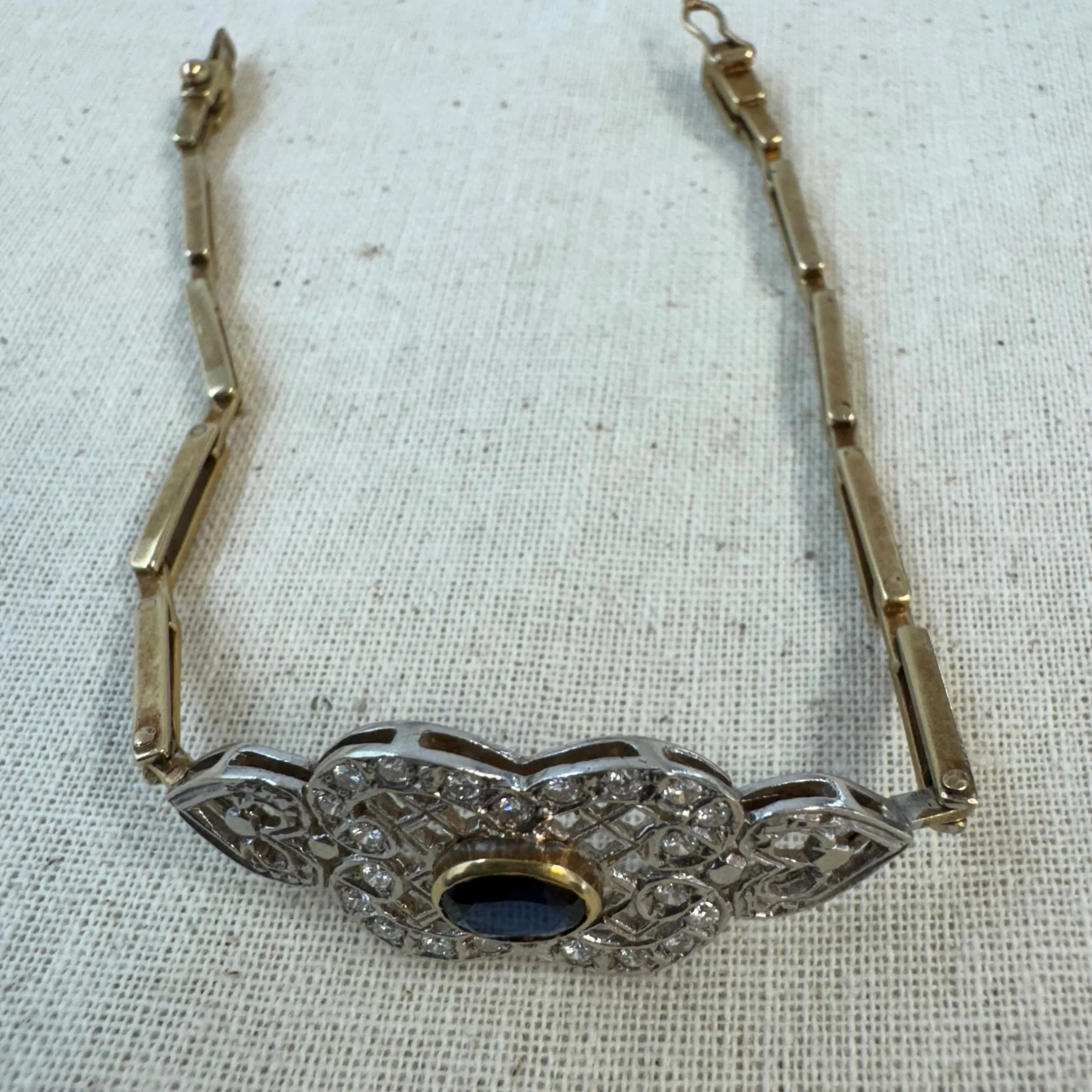 14K gold bracelet set with a central deep-blue Sapphire surrounded by sparkling Diamonds