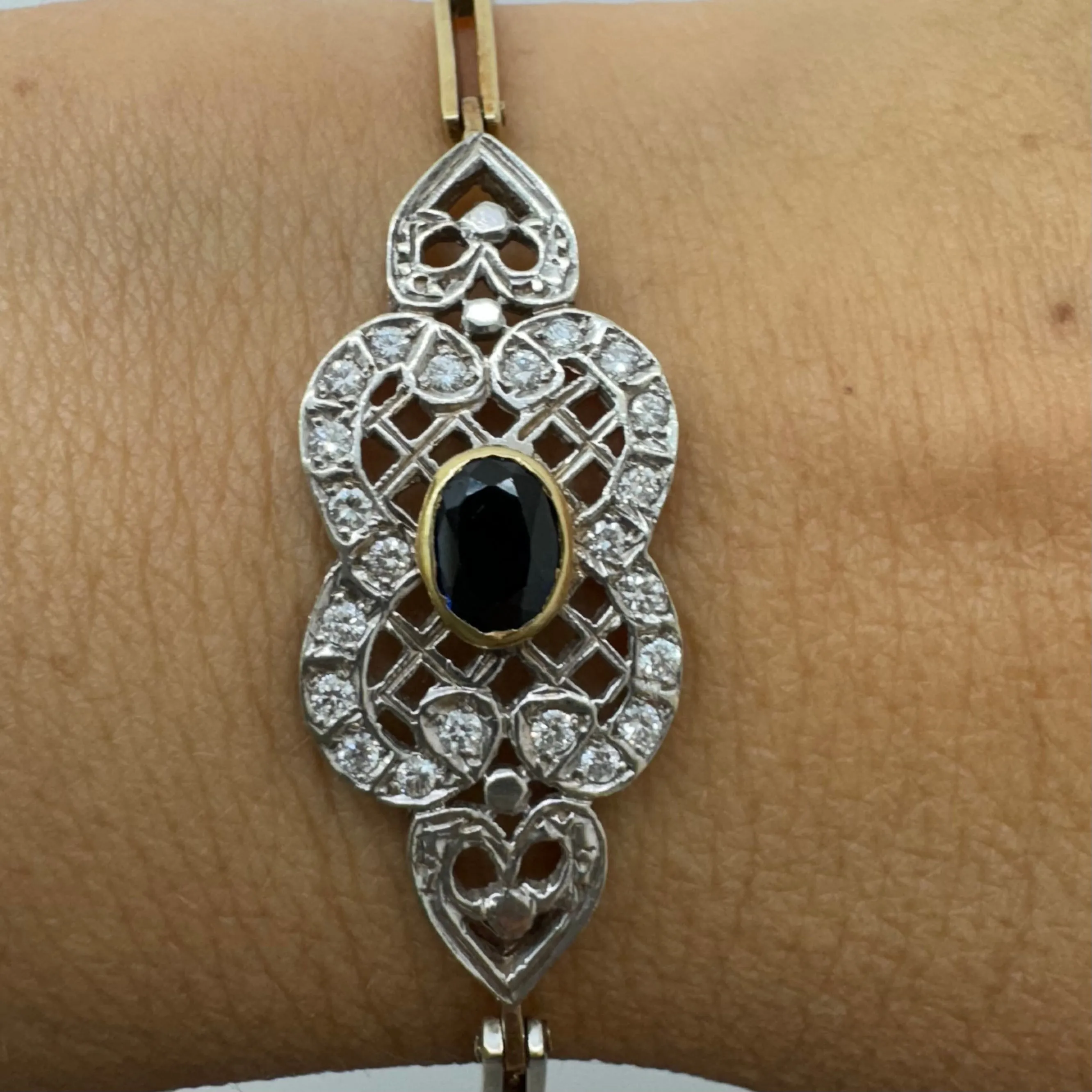 14K gold bracelet set with a central deep-blue Sapphire surrounded by sparkling Diamonds